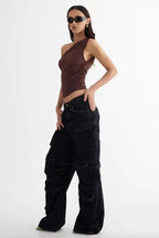 side view of woman in brown one-shoulder ruched top and dark wash wide-leg cargo pants