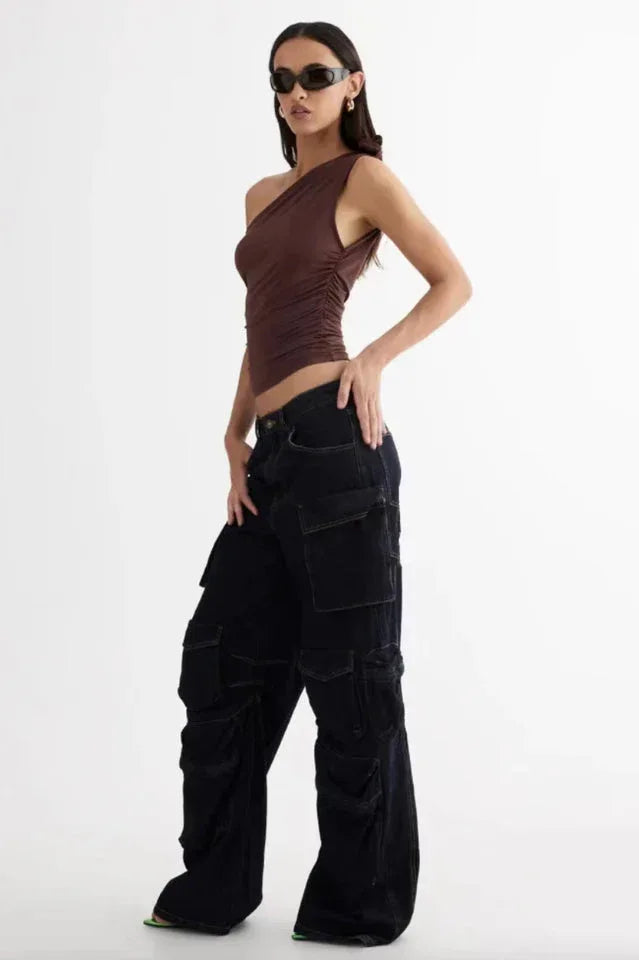 side view of woman in brown one-shoulder ruched top and dark wash wide-leg cargo pants