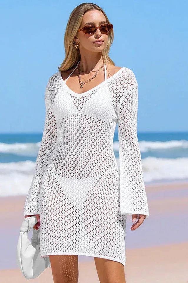 Front view of a woman in a white V-neck knit beach cover-up with long sleeves.