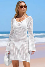 Front view of a woman in a white V-neck knit beach cover-up with long sleeves.