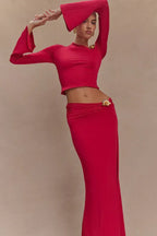 Woman in a red set posing with arms raised, showcasing the flared sleeves and silhouette.