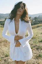 Woman in a white long-sleeved top and white skirt outdoors