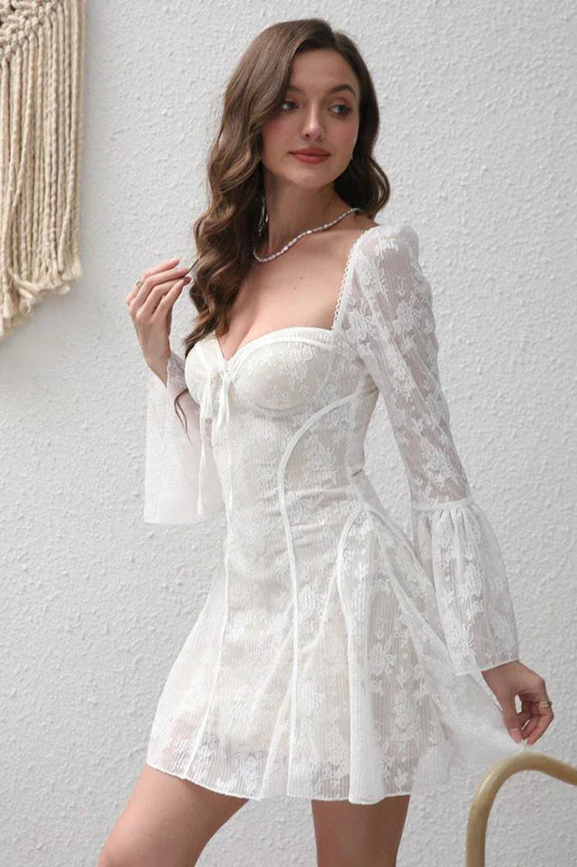 Side view of a woman in a white lace mini dress with long bell sleeves.