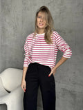 Woman wearing a white and red striped long sleeve top and black pants.