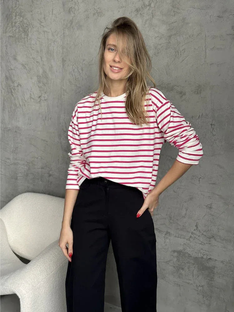 Woman wearing a white and red striped long sleeve top and black pants.