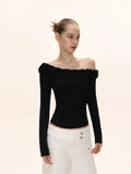 Close-up of a woman wearing a black long-sleeved ruffled off-the-shoulder top.