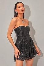 Front view of a woman modeling a black strapless sequin mini dress.