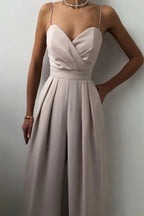Woman in a beige satin jumpsuit showing side pocket and pleated detail