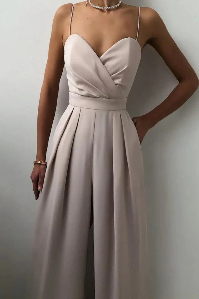 Woman in a beige satin jumpsuit showing side pocket and pleated detail