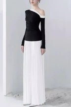 Side profile of a woman in a black and white outfit featuring an asymmetrical top and pleated trousers.