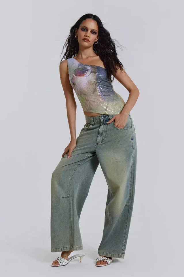 Full-body shot of a woman in a one-shoulder sequined top and wide-leg denim.
