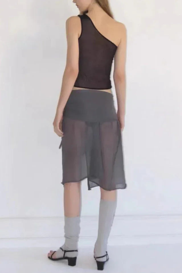 Full body view of a model in a black asymmetric one shoulder top and grey skirt