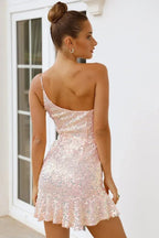 Woman wearing a pink sequin one-shoulder mini dress with a ruffled hem, viewed from the back.