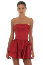Woman wearing a red strapless tiered ruffled mini dress with a lace-up back, front view