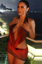 Model posing in a red and black printed halter mini dress at night