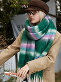 Woman wearing a tan coat and a green plaid scarf with white, pink, and blue stripes, showing the scarf's texture.
