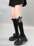 A person wearing black knee-high socks with a gray flower embellishment and bow detail, paired with platform shoes.