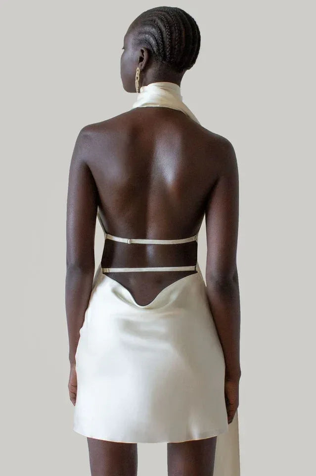 woman wearing a cream-colored satin mini dress with an open back and halter neckline from behind Main image