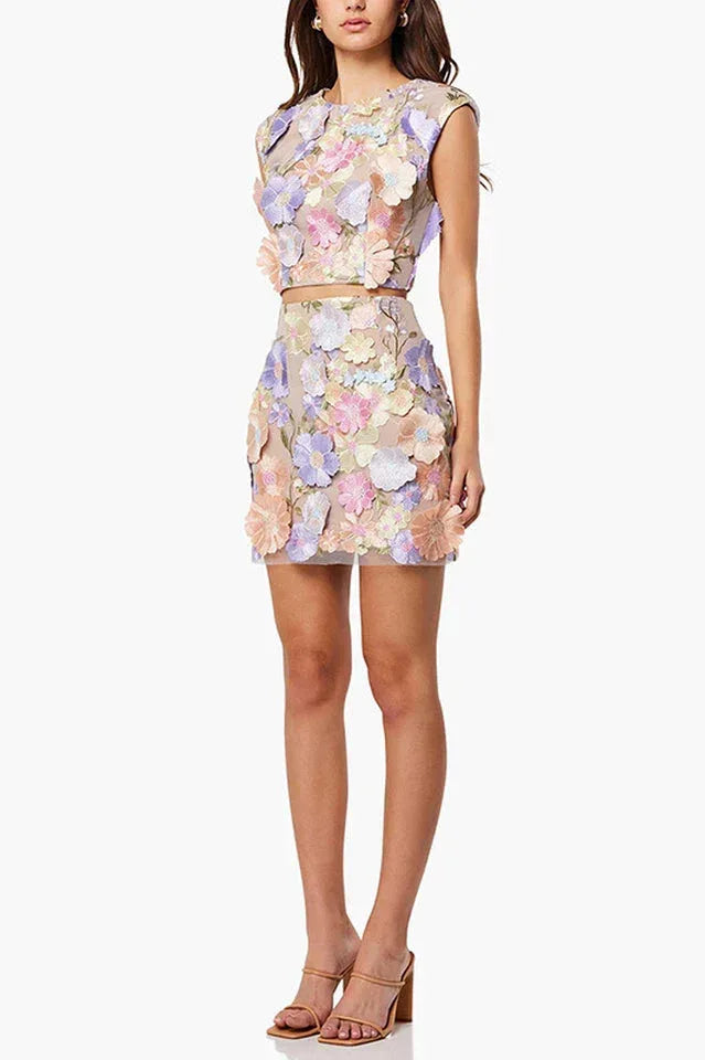 Side view of a woman in a pastel floral embroidered crop top and mini skirt set