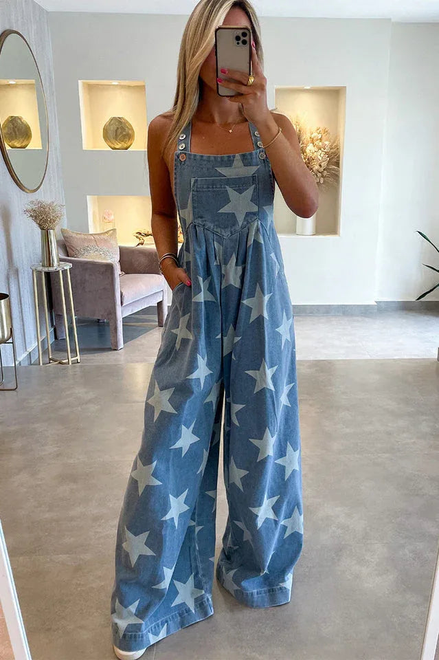 Woman wearing a light blue denim jumpsuit with a white star print and wide legs. Main image