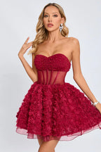 Close-up of a woman in a strapless red dress featuring a ruched and beaded bodice and a skirt made of fabric roses.
