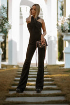 Woman wearing black jumpsuit with halter neckline and flared legs outdoors
