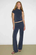 Woman wearing a navy sleeveless mock neck top and navy velour wide leg pants with a flared hem.