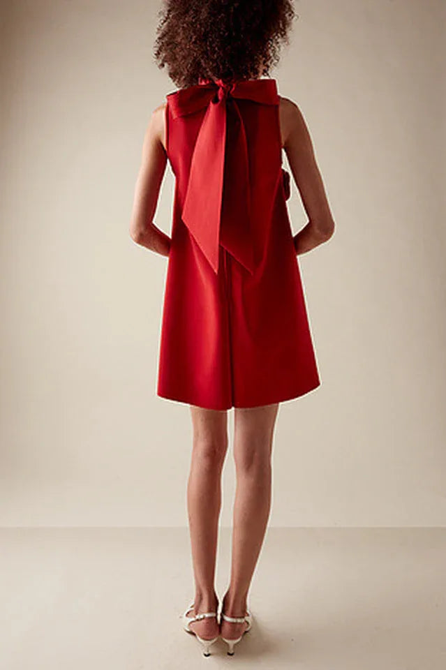 Back view of a red sleeveless A-line dress with a large bow detail at the neck.