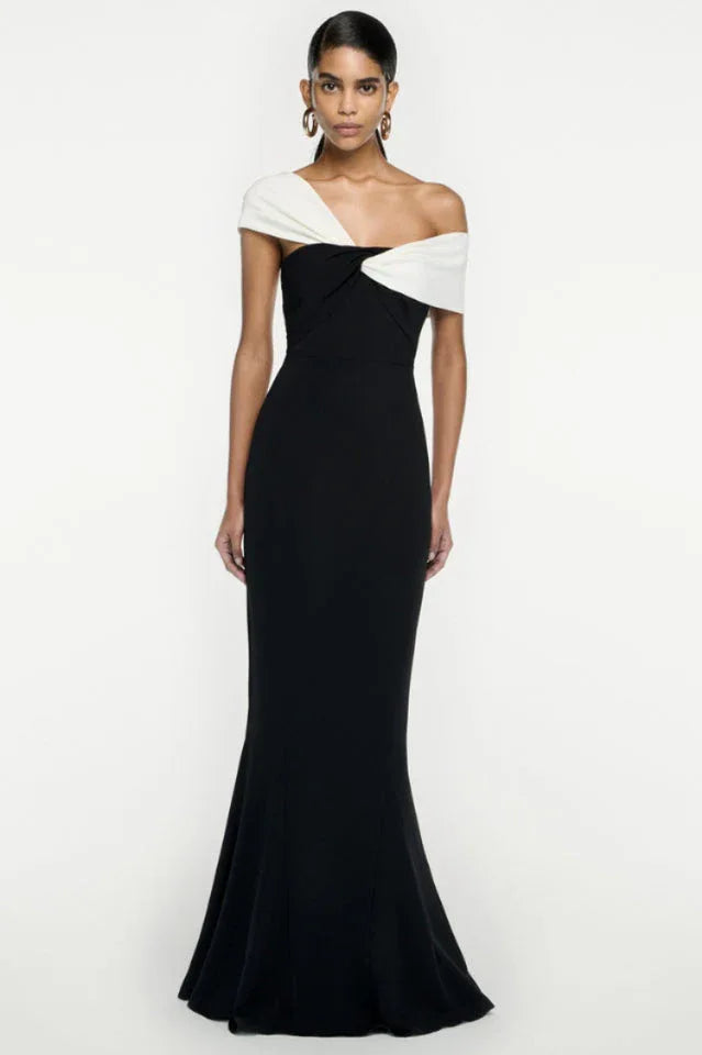 Woman wearing a black and white formal gown with an asymmetrical draped neckline and mermaid hem