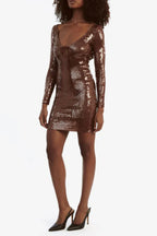Full body side view of a woman in a brown sequined long sleeve mini dress.