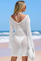 Rear view of a woman in a white knit cover-up dress with a deep V-back.