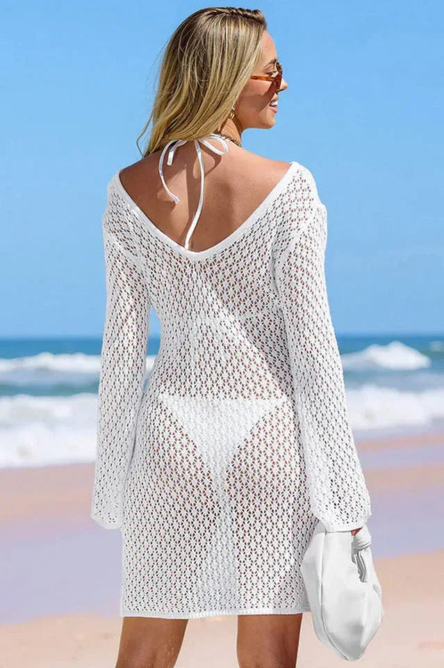 Rear view of a woman in a white knit cover-up dress with a deep V-back.