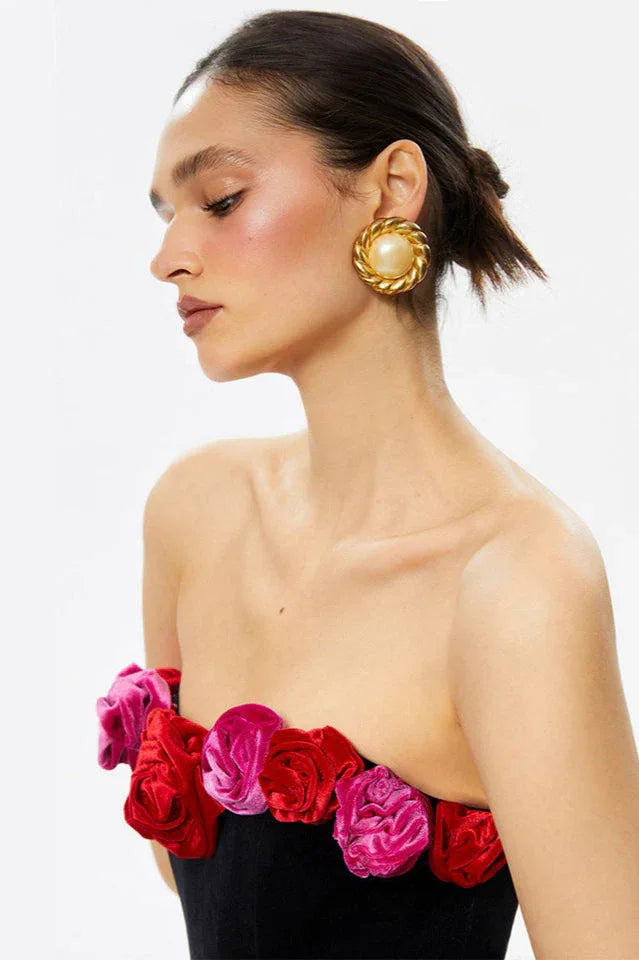 Close-up of the floral embellishment on the strapless neckline of a black velvet dress.