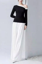 Back view of a woman modeling a black asymmetrical top and white pleated wide-leg pants.