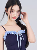 Close-up of the navy blue one-piece swimsuit neckline with light blue ruffled trim and drawstring