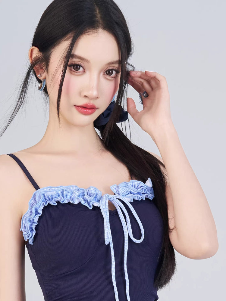 Close-up of the navy blue one-piece swimsuit neckline with light blue ruffled trim and drawstring