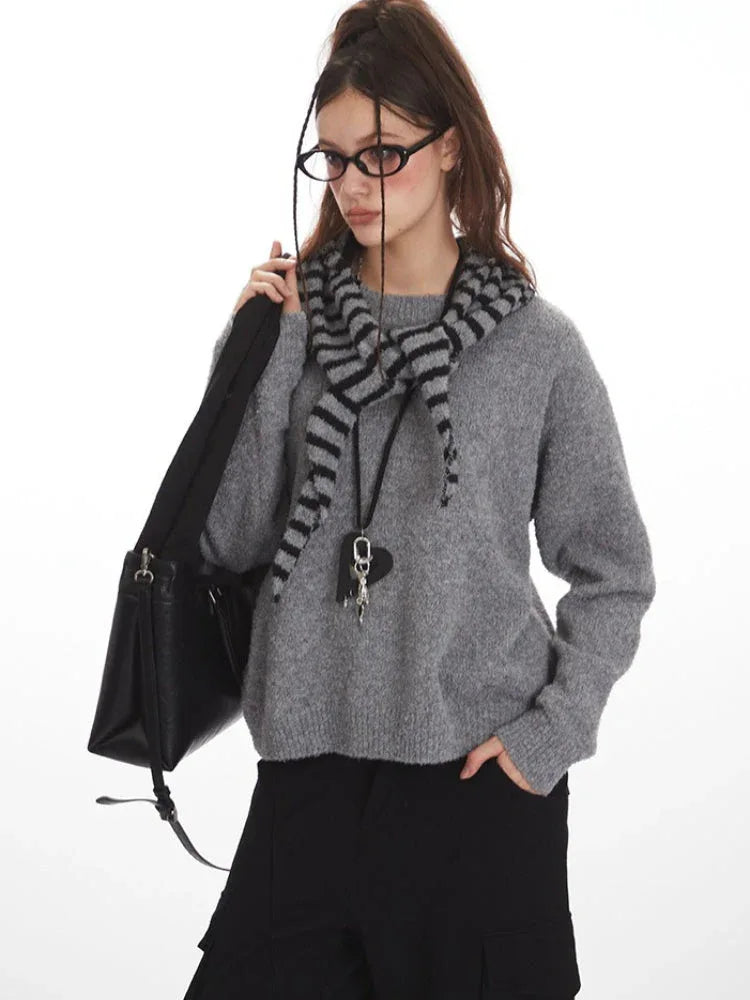 Close-up of woman in gray knit sweater with striped hood, black handbag, and pendant necklace
