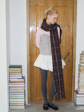 Woman wearing a plaid scarf and looking down