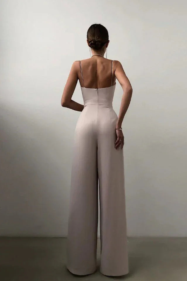 Back view of a woman in a beige satin jumpsuit with spaghetti straps and zipper closure