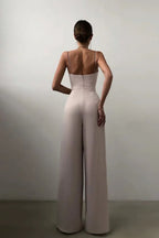 Back view of a woman in a beige satin jumpsuit with spaghetti straps and zipper closure