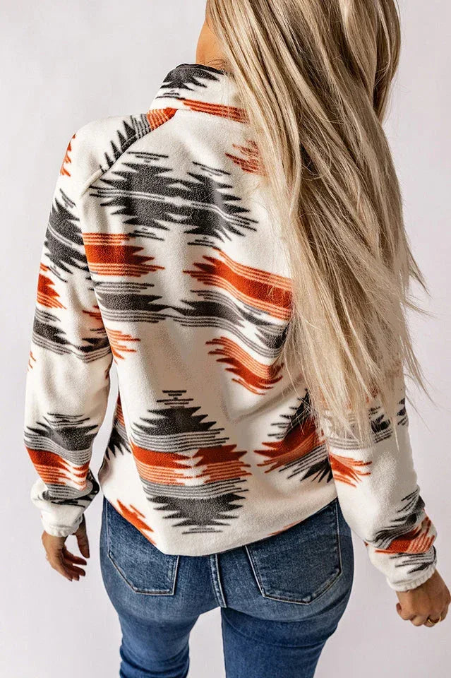 Back view of a woman wearing a cream fleece jacket with an all-over orange, black, and grey geometric print.