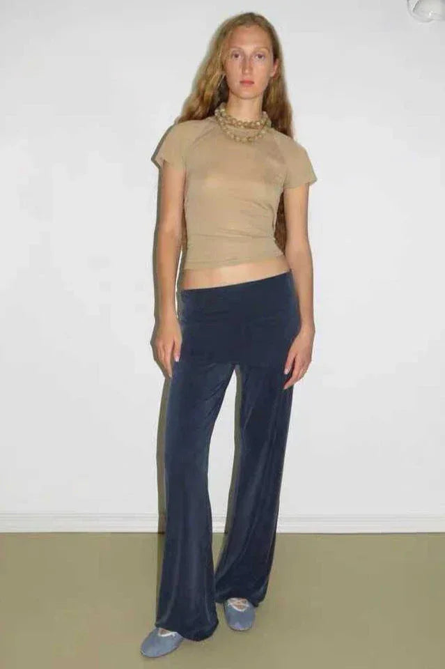 Woman wearing a tan short sleeve mock neck top and navy velour wide leg pants with a flared hem.