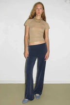 Woman wearing a tan short sleeve mock neck top and navy velour wide leg pants with a flared hem.