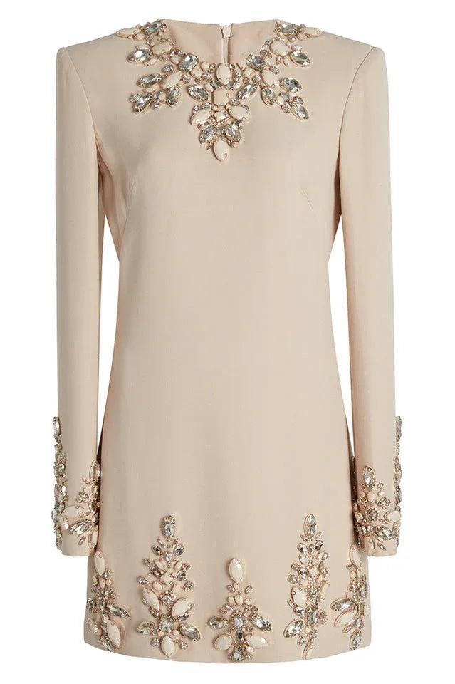 Close-up of a cream long-sleeve mini dress showcasing detailed embellishments on the neckline and hem.