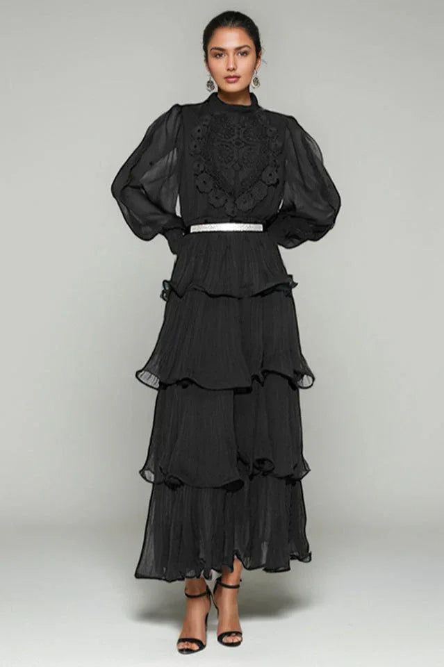 Woman wearing a black tiered chiffon maxi dress with lace detail and balloon sleeves