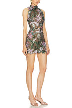 Side view of a woman modeling a short, sleeveless dress with intricate floral embroidery and sequins.