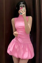 Woman in a pink sleeveless ribbed mock neck mini dress with a bubble hem skirt, taking a mirror selfie.