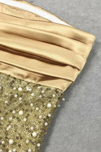 Close-up detail of the gold satin bodice and beaded sequin skirt of a gown.