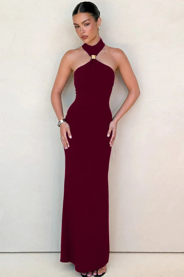 Woman in a burgundy halter neck maxi dress with a gold ring detail at the neckline. Main image