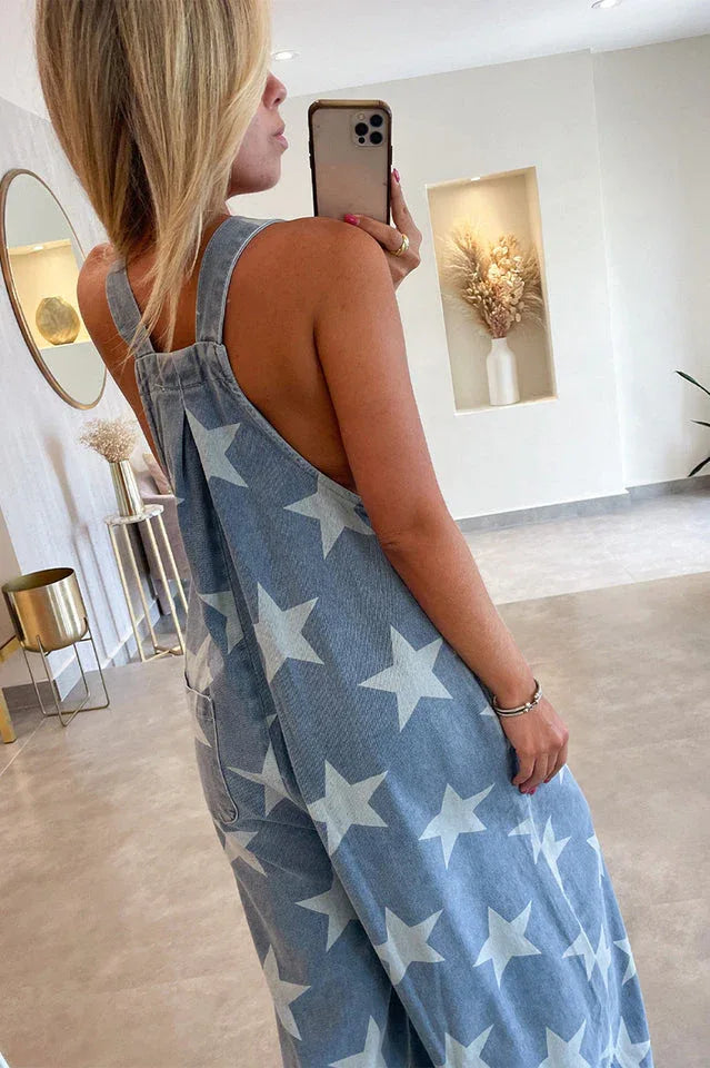 Side view of a woman showcasing the back and side of a star-print denim jumpsuit.